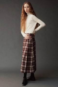 Side view of model wearing the Mijeong Park Plaid Midi Skirt in brown plaid with an ivory turtleneck