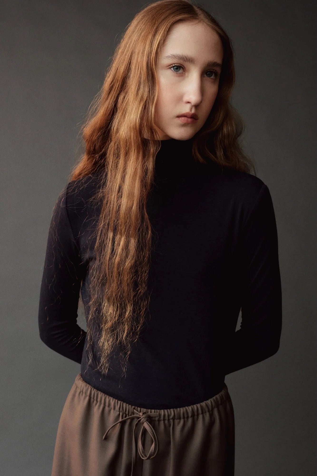Close up of the dark navy roll neck jersey top showing its fitted silhouette.