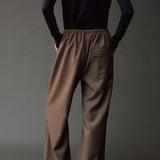 Back view of the dark navy roll neck jersey top styled with wide leg brown pants.