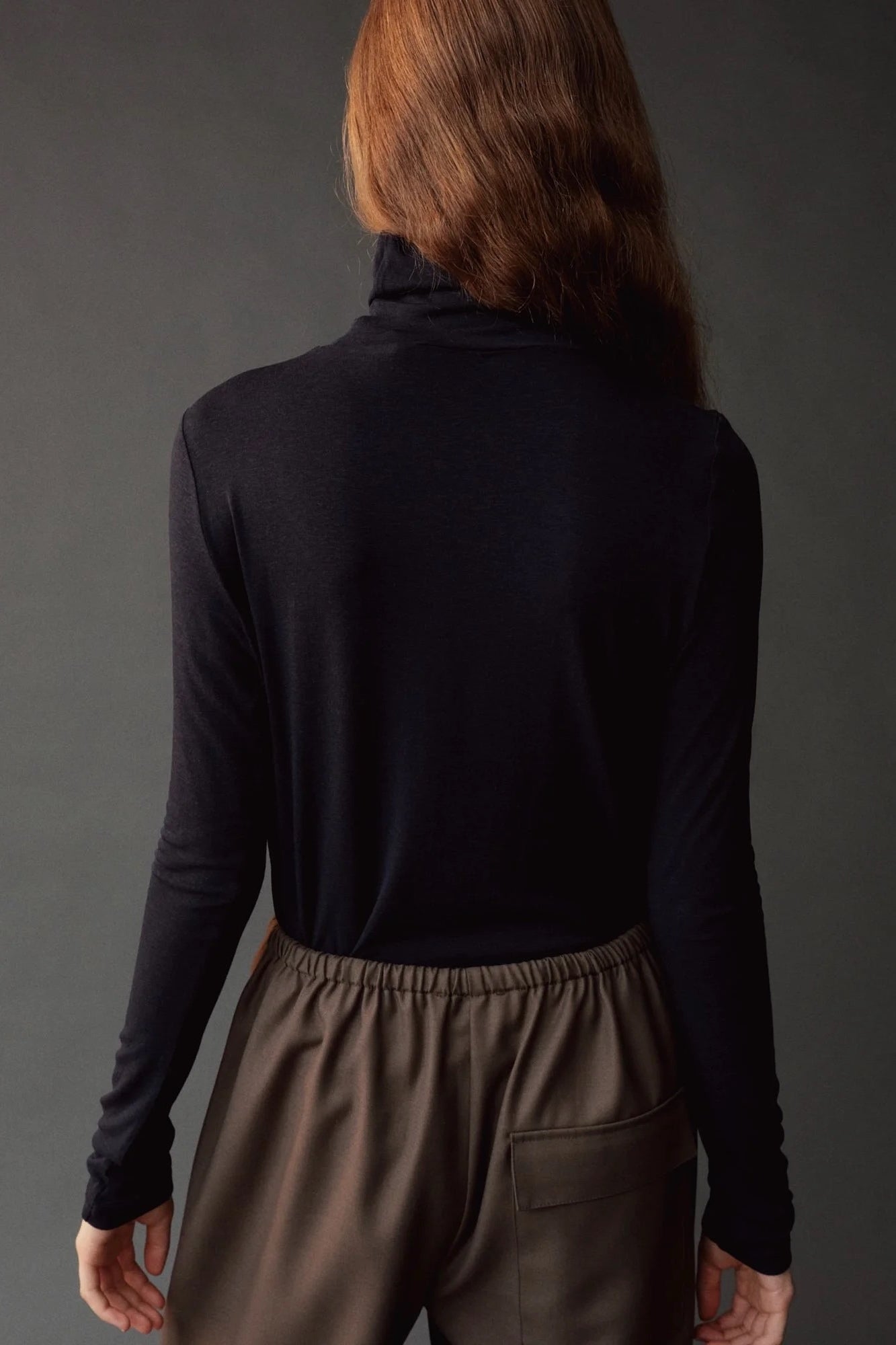 Close back view of the dark navy roll neck jersey top with slim long sleeves.
