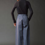Back view of the graphite roll neck jersey top styled with blue wide leg pants.