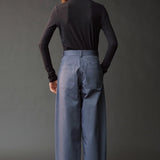 Back view of the graphite roll neck jersey top styled with blue wide leg pants.