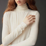 Close up of the ivory roll neck jersey top showing its softly gathered neckline.