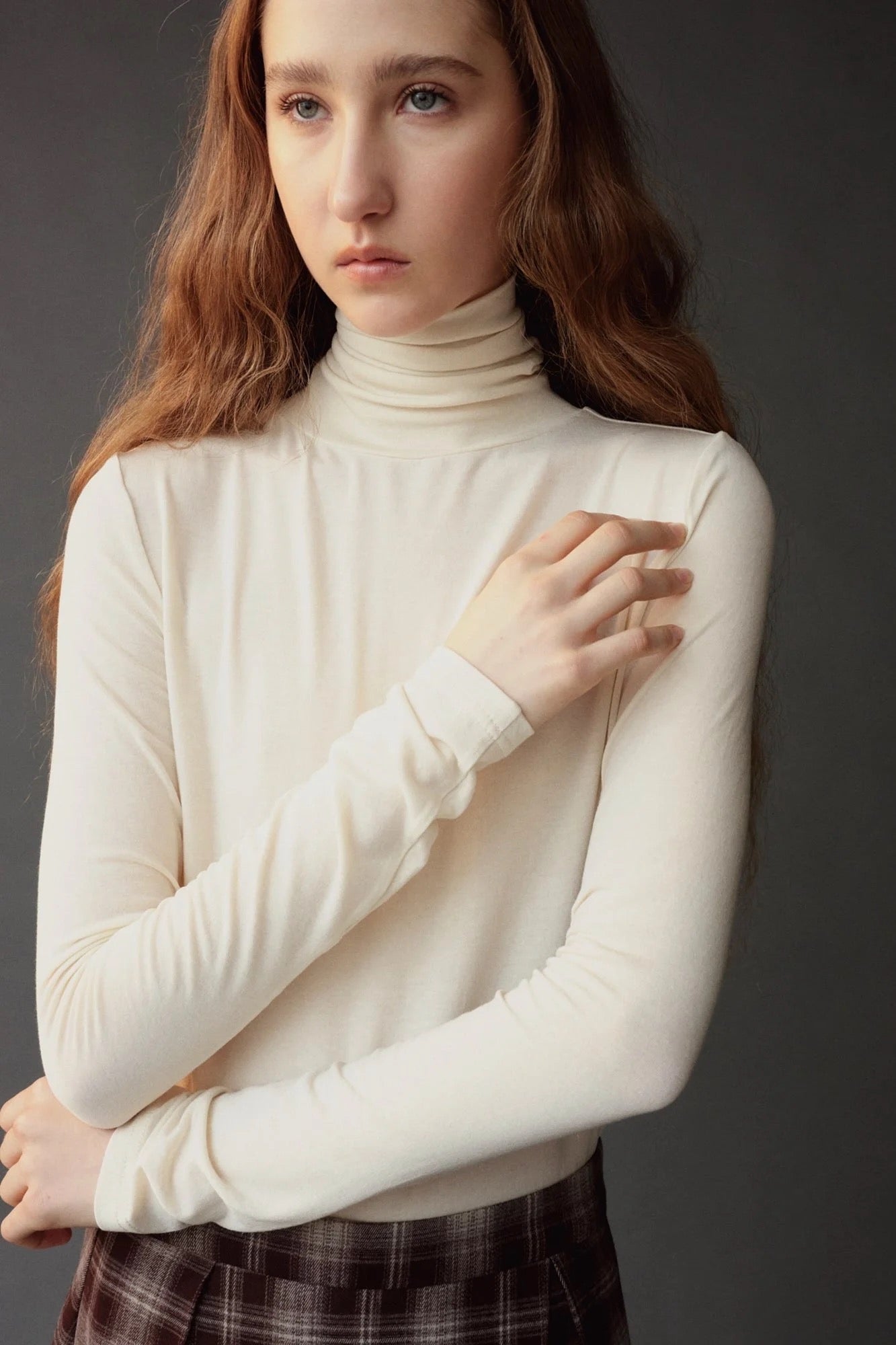 Close up of the ivory roll neck jersey top showing its softly gathered neckline.