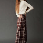 Side view of the ivory roll neck jersey top styled with a plaid midi skirt.