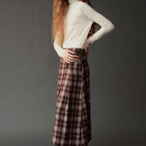 Side view of the ivory roll neck jersey top styled with a plaid midi skirt.