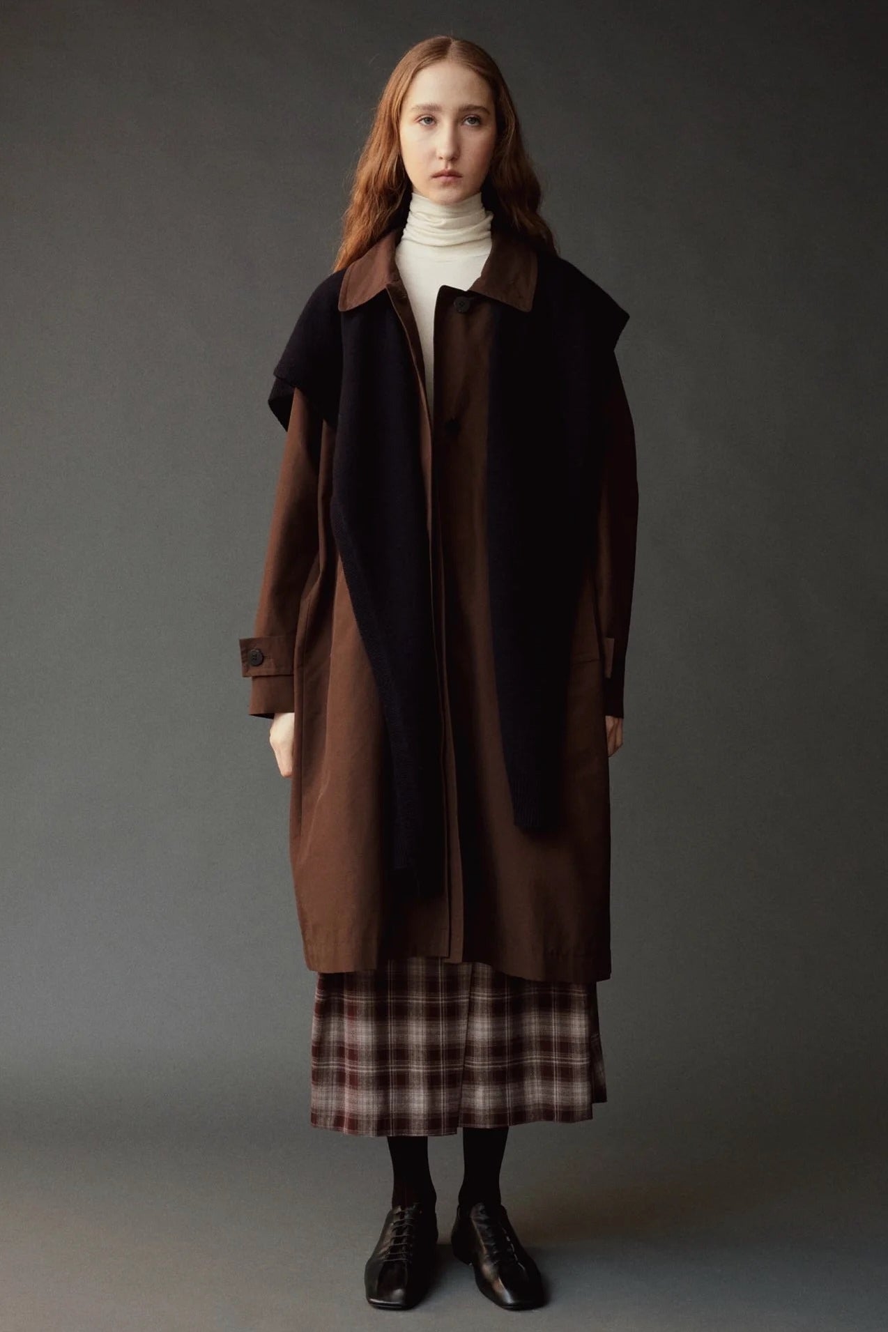 Ivory roll neck jersey top layered under a brown coat with a dark scarf.