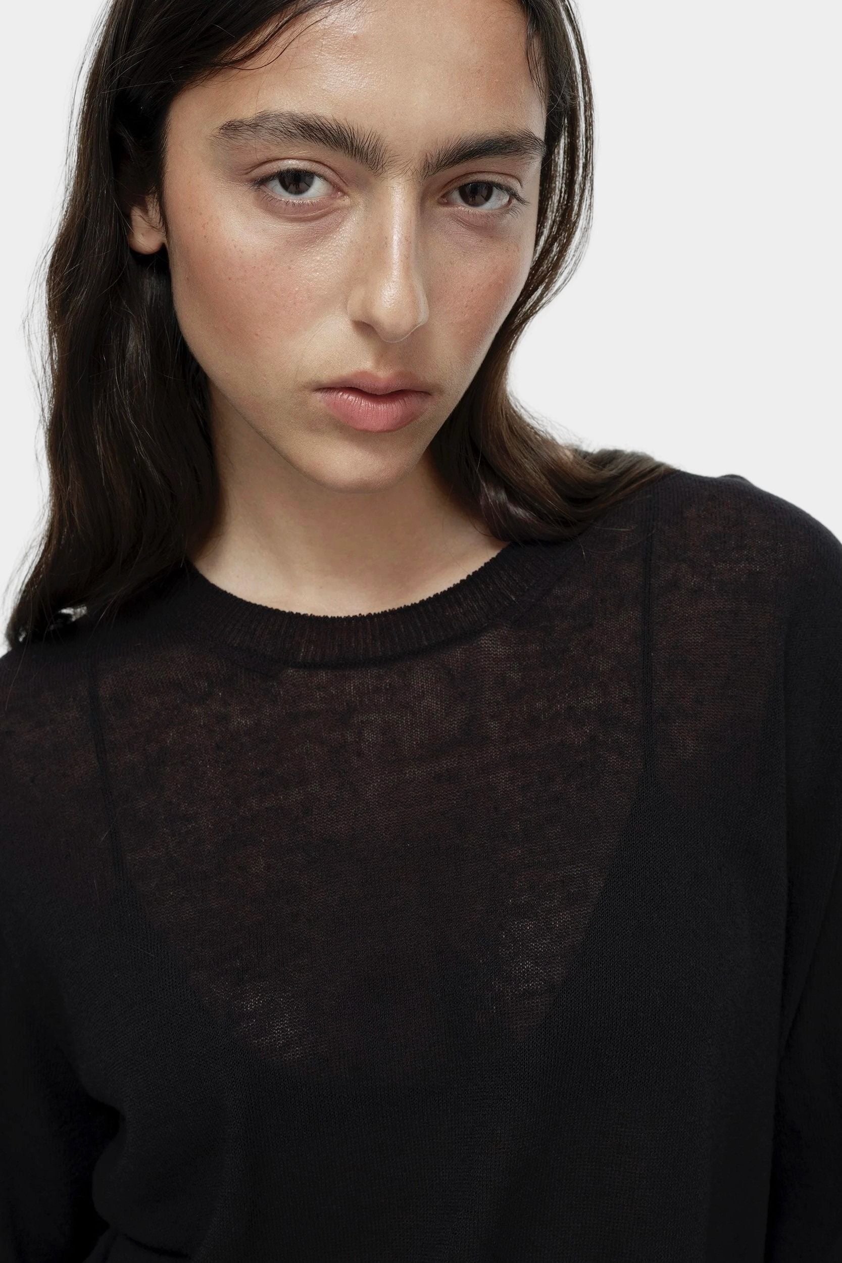 Close-up of semi sheer black linen blend knit top by Mijeong Park with crew neckline and sheer knit fabric