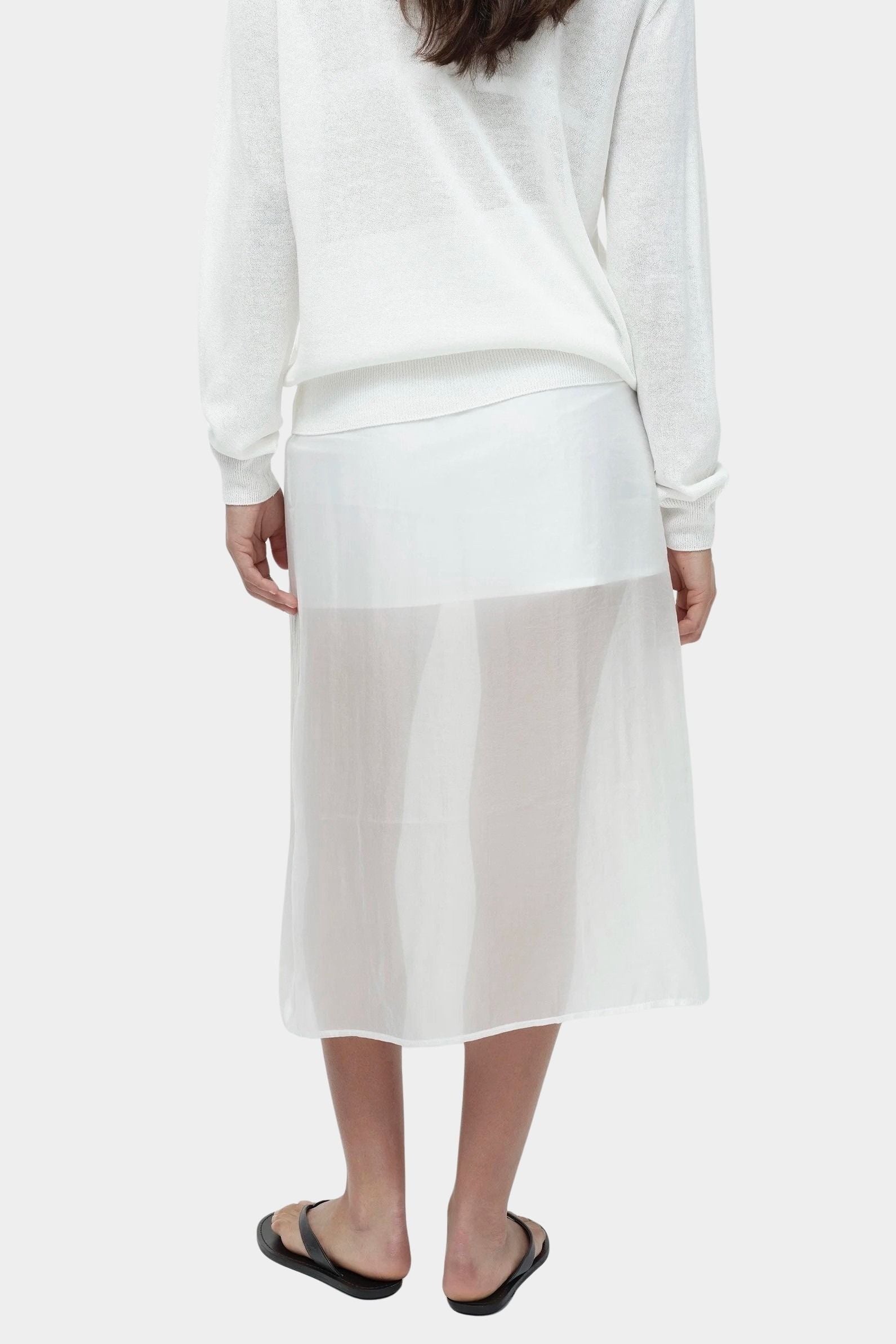 Back view of semi sheer linen blend knit top in white by Mijeong Park paired with sheer midi skirt
