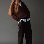 Side view of the Mijeong Park black drawstring pants styled with a brown sweater and layered shirt