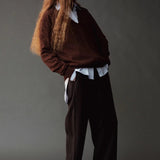 Side view of the Mijeong Park black drawstring pants styled with a brown sweater and layered shirt