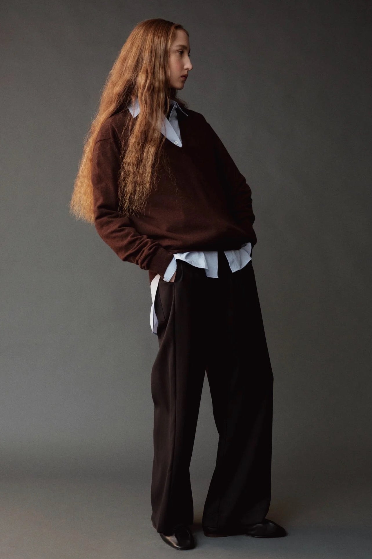Side view of the Mijeong Park black drawstring pants styled with a brown sweater and layered shirt
