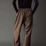 Close back view of the Mijeong Park olive brown pants showing the elastic waist and flap pocket