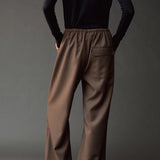 Close back view of the Mijeong Park olive brown pants showing the elastic waist and flap pocket