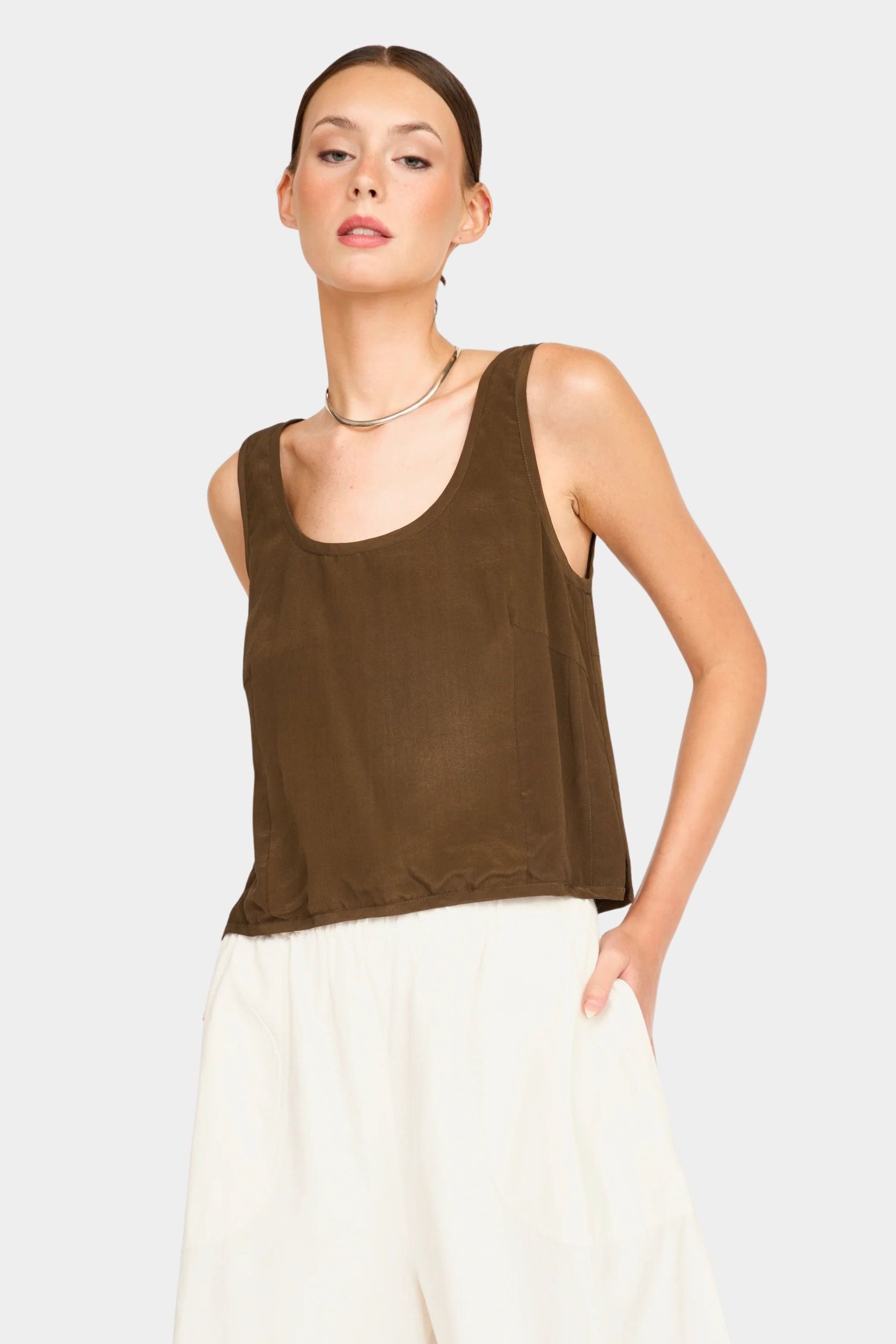 Model wearing a brown sleeveless scoop neck tank with a relaxed fit, paired with cream wide-leg pants