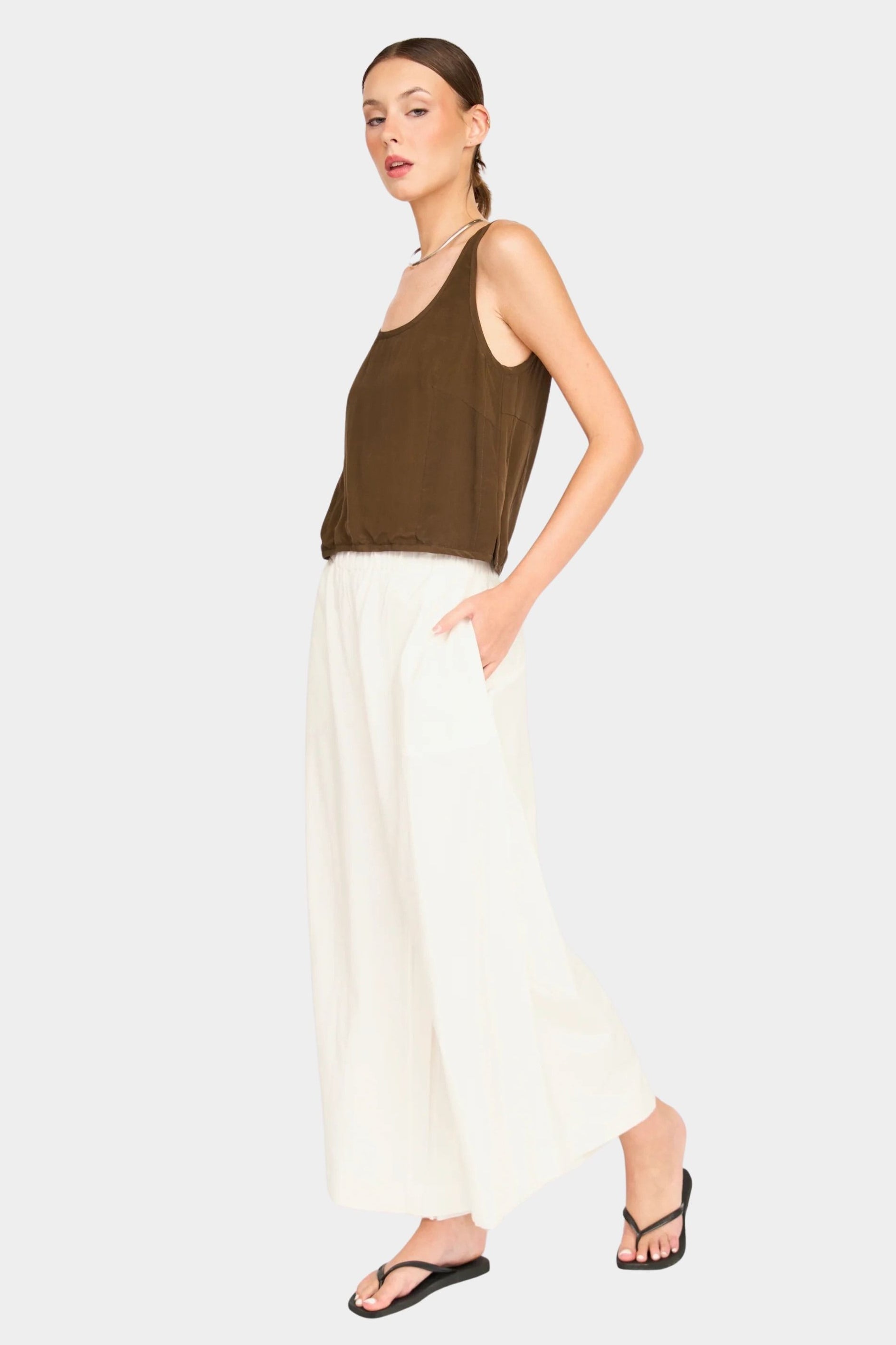 Full-body front view of brown scoop neck tank styled with cream wide-leg pants and black sandals