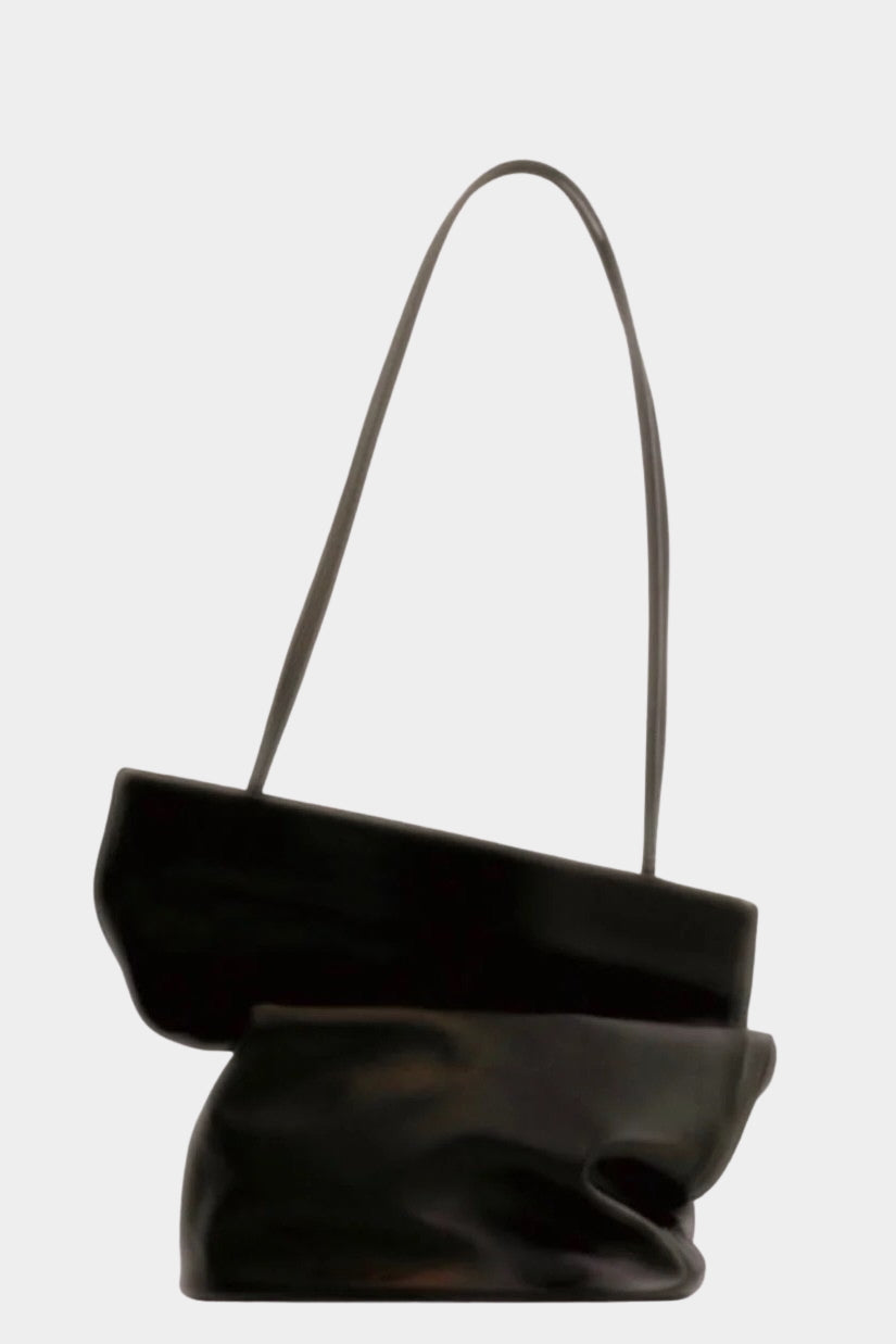 Modern Weaving Drape Oval Bucket in black leather, folded to show its fluid shape and slender straps