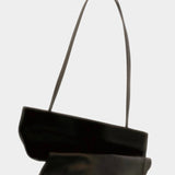 Modern Weaving Drape Oval Bucket in black leather, folded to show its fluid shape and slender straps