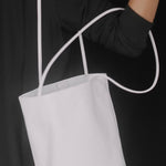 Modern Weaving Drape Oval Bucket in Creme carried by its slender straps against a black outfit