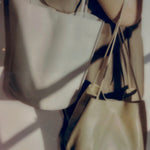 Creme Drape Oval Bucket worn over the shoulder beside a second leather bag