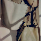 Creme Drape Oval Bucket worn over the shoulder beside a second leather bag