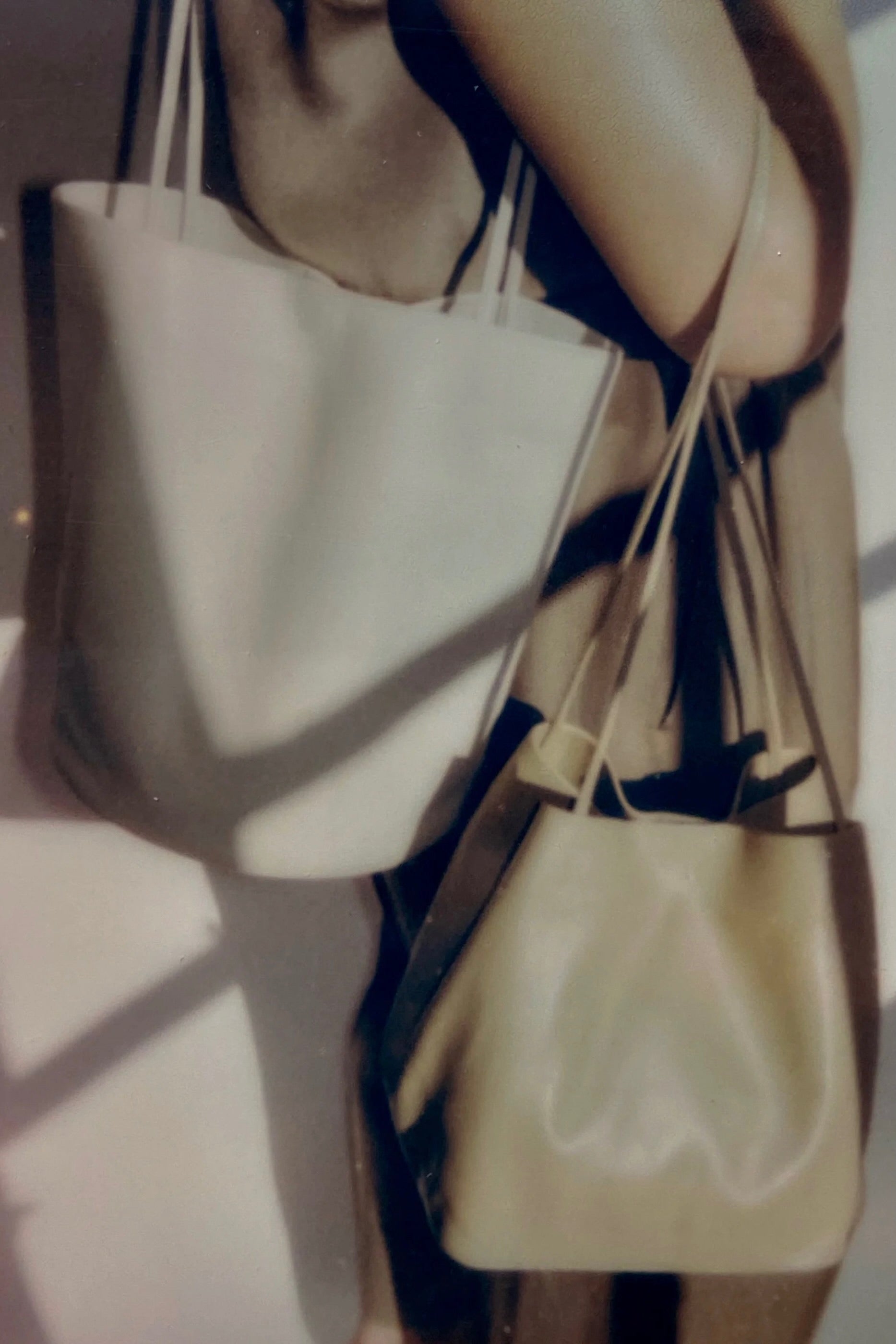 Creme Drape Oval Bucket worn over the shoulder beside a second leather bag
