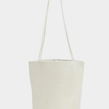 Front view of the Modern Weaving Drape Oval Bucket in Creme with long shoulder straps