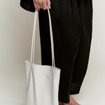 Modern Weaving Slim Elongated Tote Creme worn as shoulder bag with tall vertical silhouette and slim straps