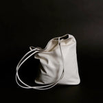 Modern Weaving Slim Elongated Tote Creme on dark background showing structured base and minimal bucket shape