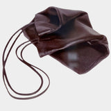 Modern Weaving Slim Lamb Sak in Braun folded on a pale surface, showing its soft leather and long straps