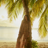 Natalie Martin Fiore Maxi Wildflower Spice beach editorial image with flowing floral silhouette and palm tree