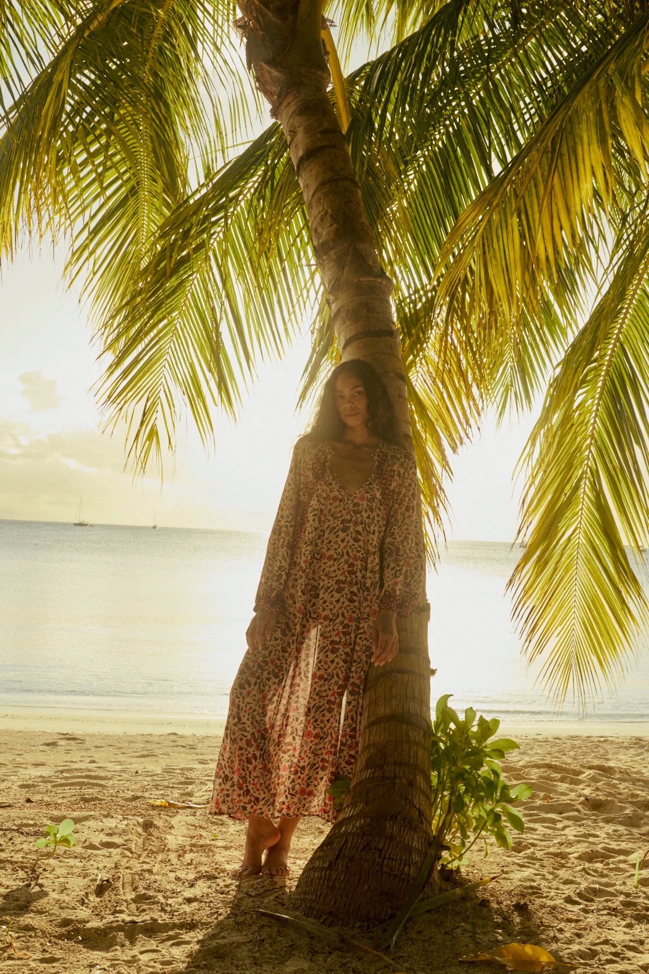 Natalie Martin Fiore Maxi Wildflower Spice beach editorial image with flowing floral silhouette and palm tree