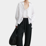 Rachel Comey Ashbolt pant in black with relaxed wide-leg silhouette, elastic drawstring waistband, and crinkled textured finish, styled with white blouse