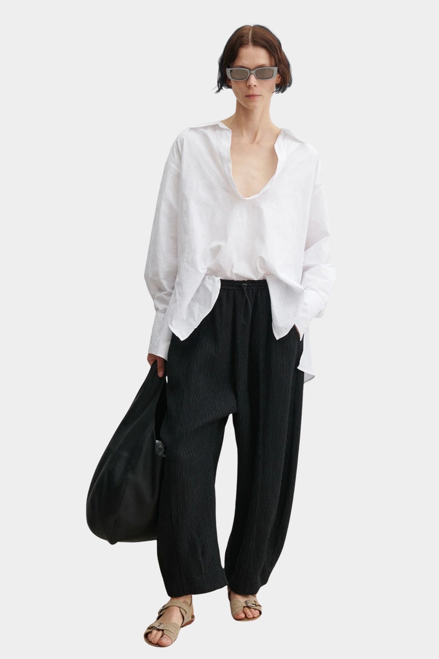 Rachel Comey Ashbolt pant in black with relaxed wide-leg silhouette, elastic drawstring waistband, and crinkled textured finish, styled with white blouse