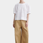 Rachel Comey rugby top in white cotton with relaxed boxy fit, wide short sleeves, and subtle panel seam detailing, styled with tan trousers