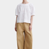 Rachel Comey rugby top in white cotton with relaxed boxy fit, wide short sleeves, and subtle panel seam detailing, styled with tan trousers