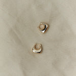 Sculptural RAGBAG Studio gold plated sterling silver Datura earrings arranged on natural textured fabric