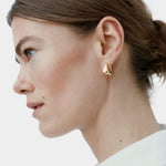 RAGBAG Studio Datura gold hoop earring worn on model in side profile, showing sculptural shape
