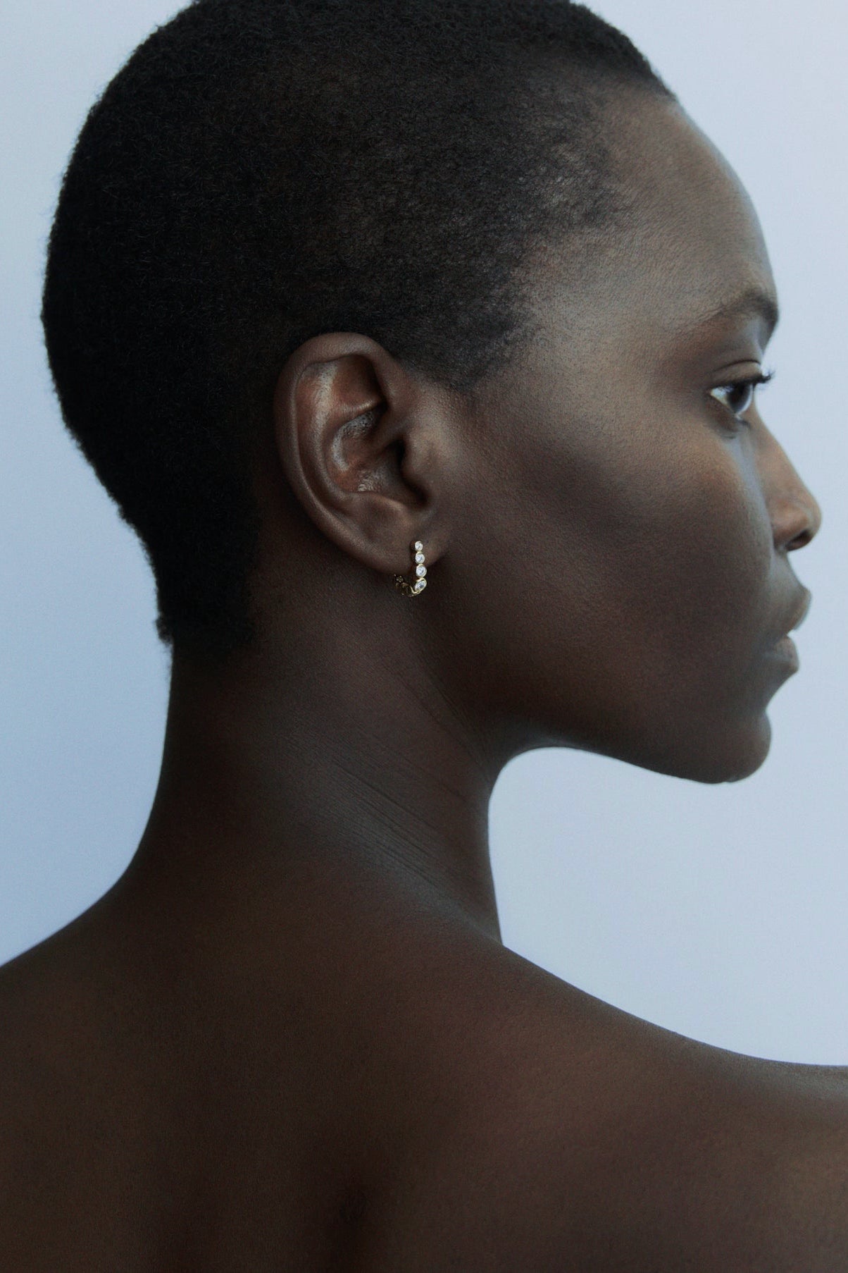 Side profile of model wearing delicate Odette gold earrings with graduated crystal settings