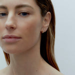 Model wearing petite gold Odette Earrings with graduated cubic zirconia stones along the earlobe