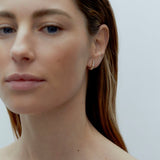 Model wearing petite gold Odette Earrings with graduated cubic zirconia stones along the earlobe