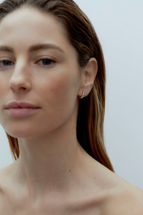 Model wearing petite gold Odette Earrings with graduated cubic zirconia stones along the earlobe