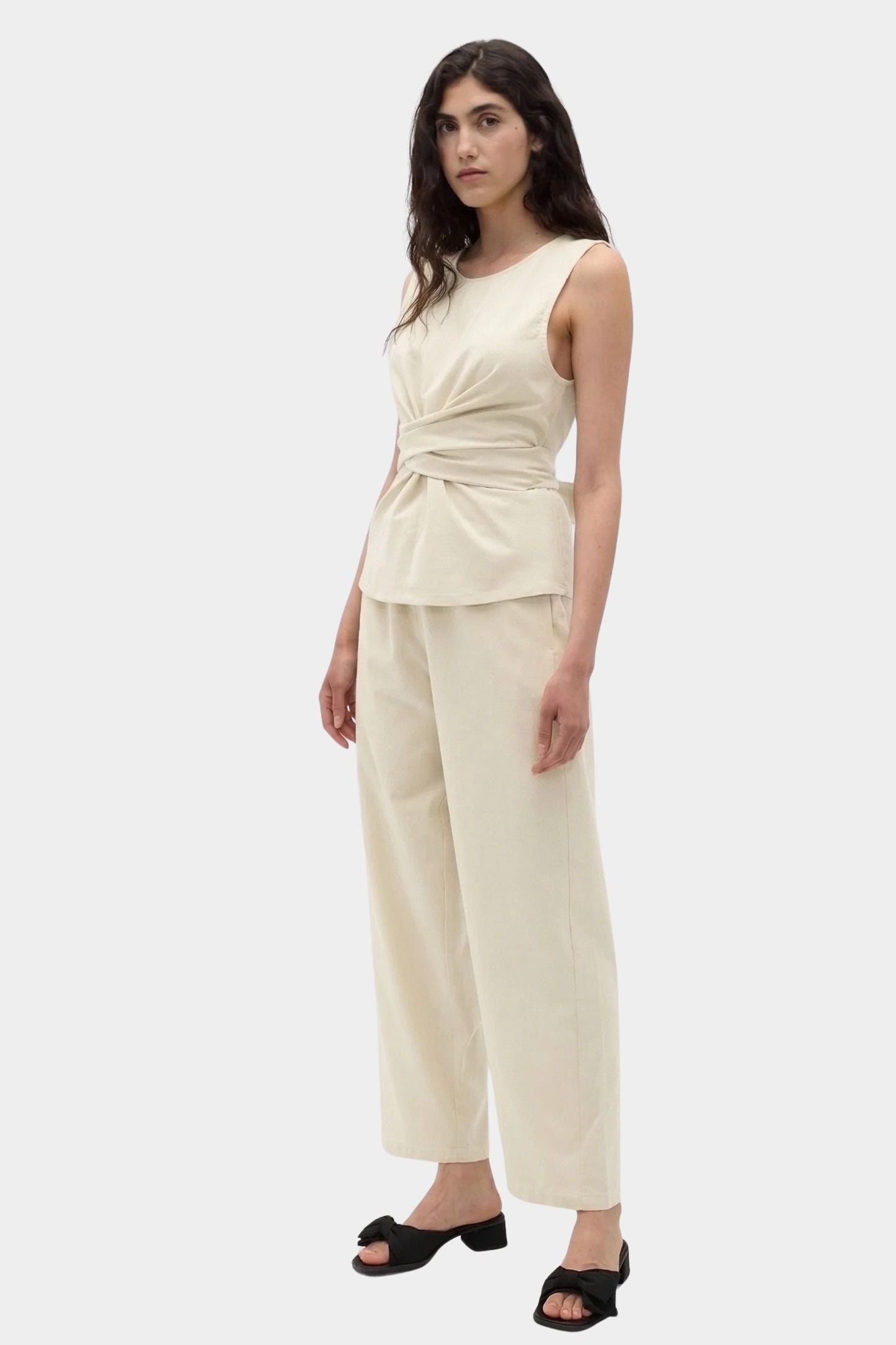 Rita Row Holan top in beige sleeveless wrap top styled with wide leg pants full outfit view